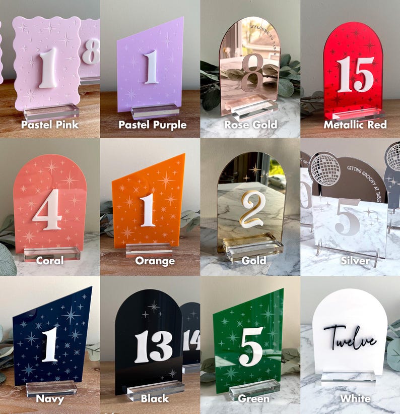 K&ouml;nnte beinhalten: Eine Sammlung von Tischnummern in verschiedenen Farben, darunter Pastellrosa, Lila, Koralle, Orange, Marineblau, Schwarz, Gr&uuml;n und Wei&szlig;. Jede Nummer wird auf einer transparenten Acrylbasis mit wei&szlig;en oder goldenen Zahlen angezeigt.
