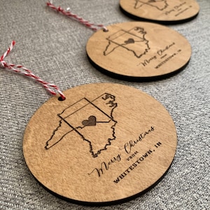 May include: Wooden Christmas ornaments with a map of Whitestown, IN, and the text "Merry Christmas from Whitestown, IN." Each ornament is round with a red and white string for hanging.