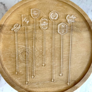 “Clear stirrers with custom text for baby shower drinks, shown in pastel-themed bar setup.”
