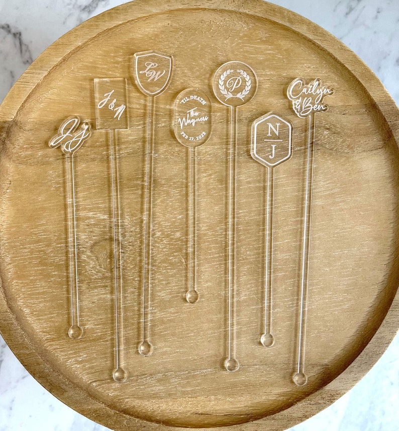 “Clear stirrers with custom text for baby shower drinks, shown in pastel-themed bar setup.”