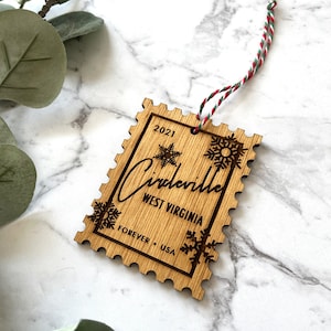 May include: A wooden Christmas ornament shaped like a postage stamp with the text "2021,  Circleville, West Virginia, Forever, USA" and snowflake designs.