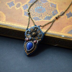 Puede incluir: Un collar de cuentas con un colgante geom&eacute;trico que presenta una piedra azul y detalles dorados.