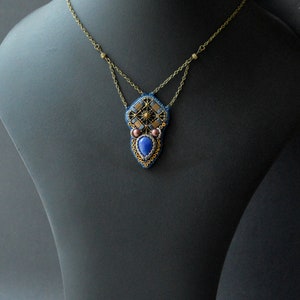 Puede incluir: Un collar de cuentas con un colgante geom&eacute;trico que presenta una piedra preciosa azul, detalles dorados y cuentas marrones.