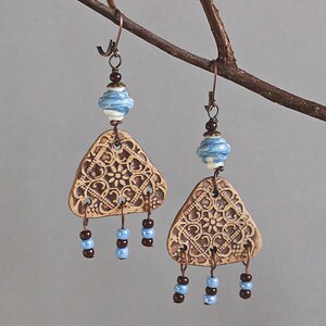 May include: A pair of brown ceramic triangle earrings with blue and white patterned beads and brown beads hanging from the bottom.