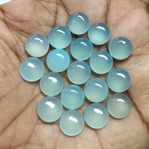 May include: A collection of 20 round, light blue, translucent cabochon gemstones. The stones are smooth and polished.