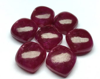 May include: Seven pink, faceted, square-shaped gemstones. The gemstones are smooth and polished.