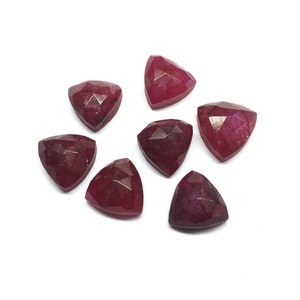 Pode incluir: Sete cabochões de rubi facetados em forma triangular. As pedras preciosas são de cor vermelha escura.