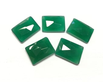 May include: Five faceted, rectangular green gemstones arranged in a circular pattern. The gems have a polished, reflective surface and are set against a white background. The gems are approximately 1 inch in length.