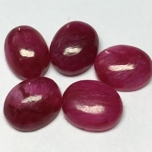 Könnte beinhalten: Fünf ovale, cabochon geschliffene, rosafarbene Edelsteine. Die Edelsteine haben eine glatte, polierte Oberfläche und einen leichten Schimmer.