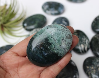 May include: A collection of green moss agate tumbled stones. The stones are smooth and polished, with a variety of green and white patterns.