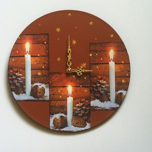 May include: Round wall clock with a brown face featuring three lit candles, pinecones, and stars. The clock hands are gold-colored. The background has a wood-like texture, creating a warm, festive feel. A decorative item for the home.