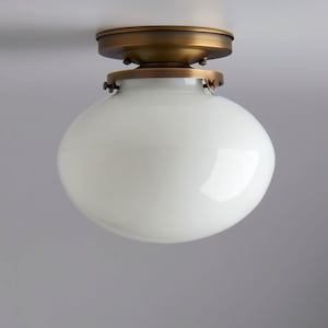 May include: A white glass globe ceiling light fixture with a brass finish. The light has a simple design with a round globe and a circular base.