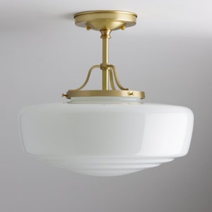 May include: A ceiling light with a white, bowl-shaped glass shade and brass-toned metal fittings. The shade has a smooth, glossy finish and a stepped design. The light fixture is designed for indoor use.