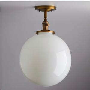 May include: A brass ceiling light fixture with a white globe shade.