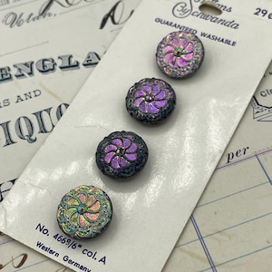 May include: Four iridescent buttons on a white card, labelled "Buttons By Schawanda." The buttons have a floral design with a metallic sheen, in shades of purple, pink, and green. The card reads "Guaranteed Washable" and "Western Germany."