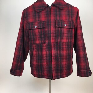 May include: A red and black plaid jacket with a full zipper closure, two front pockets, and buttoned cuffs. The jacket is displayed on a mannequin and has a classic, outdoorsy style.