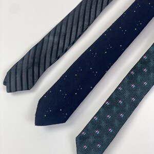 May include: Three neckties with different patterns. One is black with white stripes, one is dark blue with white dots, and one is teal with pink and white dots.