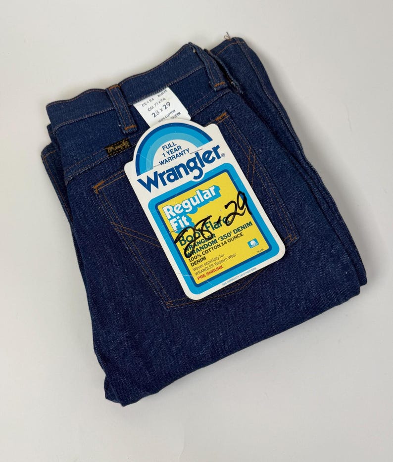 Puede incluir: Vaqueros Wrangler azul oscuro doblados con etiqueta. La etiqueta dice "Regular Fit" y "28 x 29". La etiqueta tambi&eacute;n indica "100% Algod&oacute;n 14 Onzas Denim". Los vaqueros son pre-encogidos.