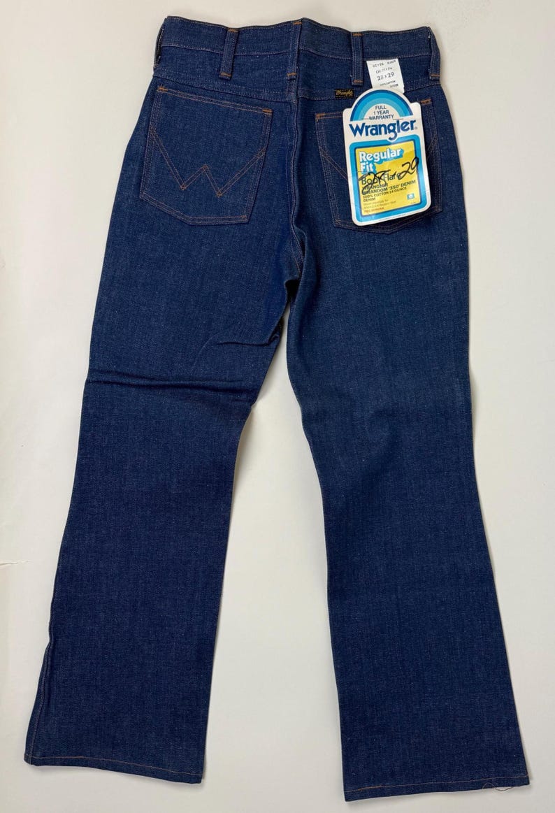 Puede incluir: Vaqueros Wrangler azul oscuro de corte Regular Fit con etiqueta. Los vaqueros tienen un dise&ntilde;o cl&aacute;sico de cinco bolsillos, cremallera y el logo de Wrangler en el bolsillo trasero. La etiqueta indica una cintura de 76 cm y un largo de 74 cm.