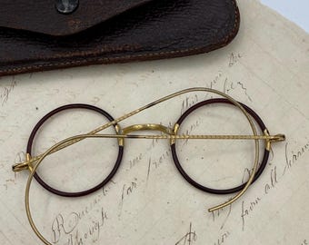 Okulary przeciwsłoneczne z lat 20. XX wieku w kolorze ceglasto-czerwonym, okrągłe, celuloidowe, wypełnione złotem