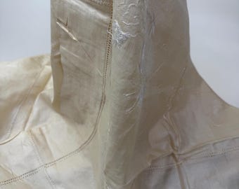 May include: Off-white fabric with embroidered floral and cloud designs. The fabric has a stitched border and a patchwork design. The embroidery is in a lighter shade of off-white, creating a subtle contrast. The fabric is draped, showing its texture and design.
