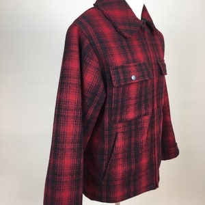 May include: A red and black plaid jacket with a collared neckline and two front pockets. The jacket has a zipper closure and buttoned cuffs. The fabric appears to be a thick, warm material, suitable for cooler weather.