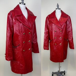 May include: A vibrant red double-breasted coat with gold-colored buttons. The coat has a glossy, textured finish and a classic lapel collar. The coat is displayed on a mannequin.