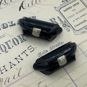 Peut inclure: Deux boucles d'oreilles en plastique noir torsadé avec des accents argentés.