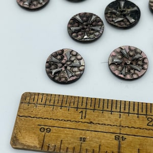 May include: A collection of 10 round, iridescent, black and silver buttons with a starburst design. The buttons are approximately 1 inch in diameter and are shown next to a ruler.
