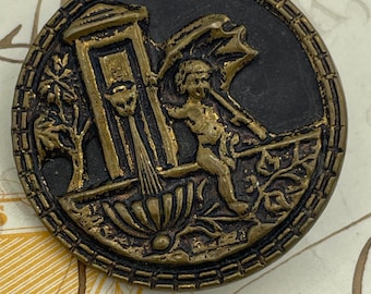 Bottone con immagine in metallo ottone raffigurante un putto Cupido in ottone antico alla fontana