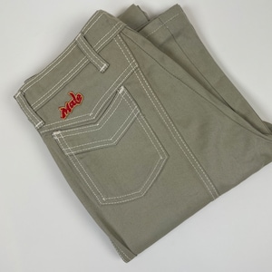 Könnte beinhalten: Eine hellgrüne Hose mit weißen Nähten und einem roten "Mole"-Logo auf der Gesäßtasche.