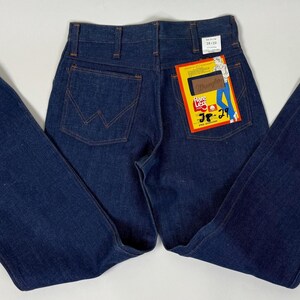 Pode incluir: Cal&ccedil;as de ganga azul escuro com design de perna larga. As cal&ccedil;as de ganga t&ecirc;m um estilo cl&aacute;ssico de cinco bolsos e uma etiqueta Lee Jeans presa ao bolso de tr&aacute;s. As cal&ccedil;as de ganga est&atilde;o colocadas numa superf&iacute;cie branca.
