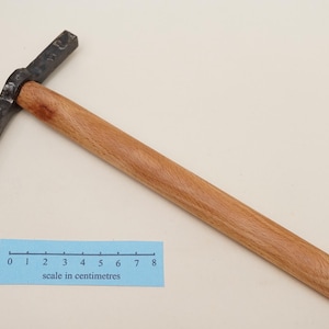 Può includere: Un martello con manico in legno e testa in metallo nero. Il martello è lungo 28 centimetri.