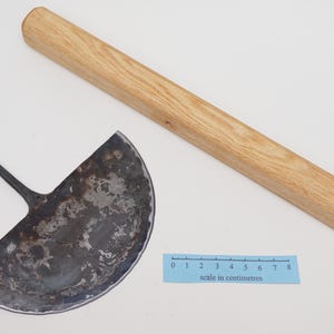 May include: A half-circle shaped metal tool with a wooden handle. The tool is used for cutting and shaping clay. The handle is about 30 cm long.