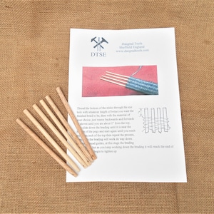 Puede incluir: Un juego de ocho clavijas de madera para trenzar, junto con instrucciones sobre cómo usarlas. Las instrucciones incluyen un diagrama del proceso de trenzado.
