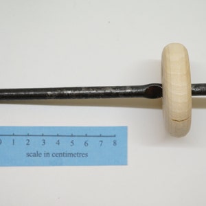 K&ouml;nnte beinhalten: Ein Werkzeug aus Holz und Metall mit einem langen, d&uuml;nnen Metallstab und einem runden Holzgriff. Der Griff hat ein Loch in der Mitte und ist mit dem Stab verbunden. Ein Lineal ist auf dem Bild zu sehen, das zeigt, dass das Werkzeug etwa 8 Zentimeter lang ist.