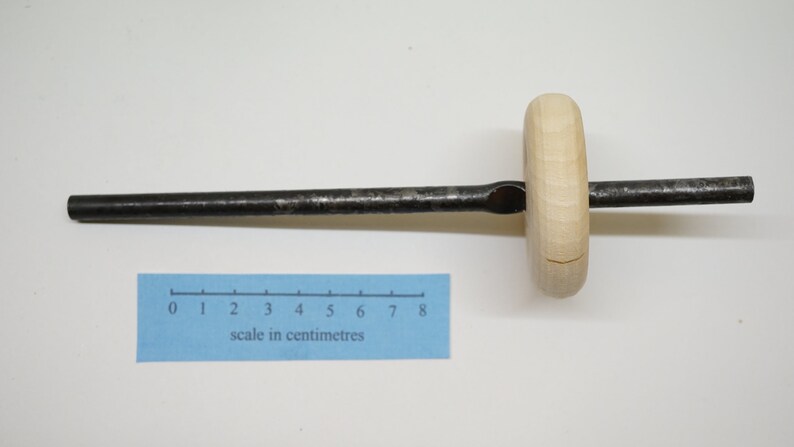 K&ouml;nnte beinhalten: Ein Werkzeug aus Holz und Metall mit einem langen, d&uuml;nnen Metallstab und einem runden Holzgriff. Der Griff hat ein Loch in der Mitte und ist mit dem Stab verbunden. Ein Lineal ist auf dem Bild zu sehen, das zeigt, dass das Werkzeug etwa 8 Zentimeter lang ist.