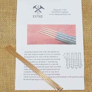 Puede incluir: Cinco agujas de tejer de metal dorado con una hoja de instrucciones de papel blanco. Las instrucciones incluyen el texto "DTSE" y "Daegrad Tools Sheffield England www.daegradtools.com".