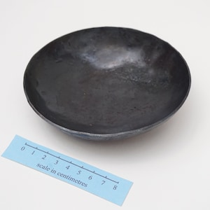 Puede incluir: Un cuenco de metal negro con un borde ligeramente redondeado. El cuenco tiene un di&aacute;metro de aproximadamente 8 cent&iacute;metros.