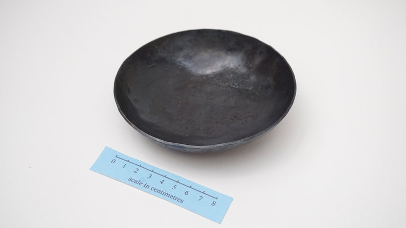Puede incluir: Un cuenco de metal negro con un borde ligeramente redondeado. El cuenco tiene un di&aacute;metro de aproximadamente 8 cent&iacute;metros.