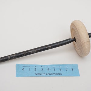 K&ouml;nnte beinhalten: Ein Holzrad mit einer daran befestigten Metallstange. Die Stange ist etwa 20 cm lang. Das Rad hat einen Durchmesser von etwa 5 cm.