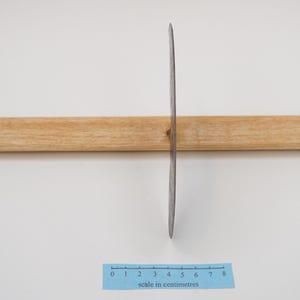 May include: A silver knife with a wooden handle, measuring 20 cm long, is positioned on a white surface with a ruler for scale.