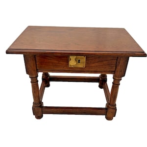 May include: A dark brown wooden end table with a single drawer and turned legs. The drawer has a brass pull with a keyhole.