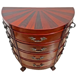 May include: A half-round mahogany chest of drawers with five drawers and brass hardware. The top of the chest is inlaid with a sunburst pattern.