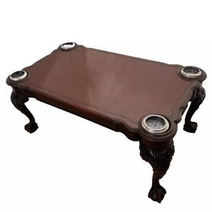 May include: A dark brown wooden coffee table with four carved legs and four silver-colored cup holders.