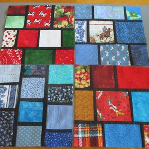 May include: A patchwork quilt with a variety of colorful fabrics, including red, blue, green, and brown. The quilt is made up of squares and rectangles, and the seams are outlined in black. The quilt is a great example of a traditional patchwork design.