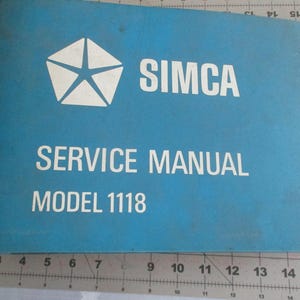 May include: A blue Simca Service Manual for Model 1118. The cover features the Simca logo, a white starburst design, and the words "SIMCA", "SERVICE MANUAL", and "MODEL 1118" in white lettering. The manual is on a measuring surface.