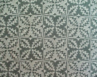 May include: Close-up of a fabric with a repeating pattern of stylized leaves in a grid. The leaves are a muted green color, set against a cream-colored background with small dotted details.