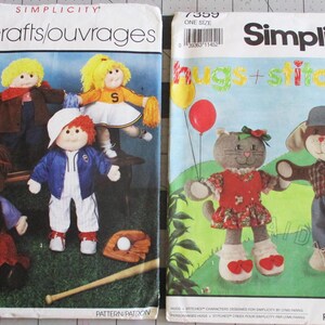 May include: Two Simplicity sewing patterns for making dolls. The first pattern is for a group of four dolls, including a girl with a red dress, a girl with a blue dress, a girl with a white dress, and a boy with a blue and white outfit. The second pattern is for two dolls, a cat with a red and white dress and a dog with a plaid shirt and blue pants. The patterns are titled "crafts/ouvrages" and "hugs + stitches".