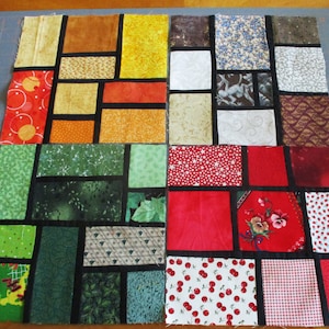 May include: A patchwork quilt with a stained glass design. The quilt is made up of squares of different fabrics in various colors, including red, green, yellow, and brown. The squares are sewn together with black fabric to create a stained glass effect.